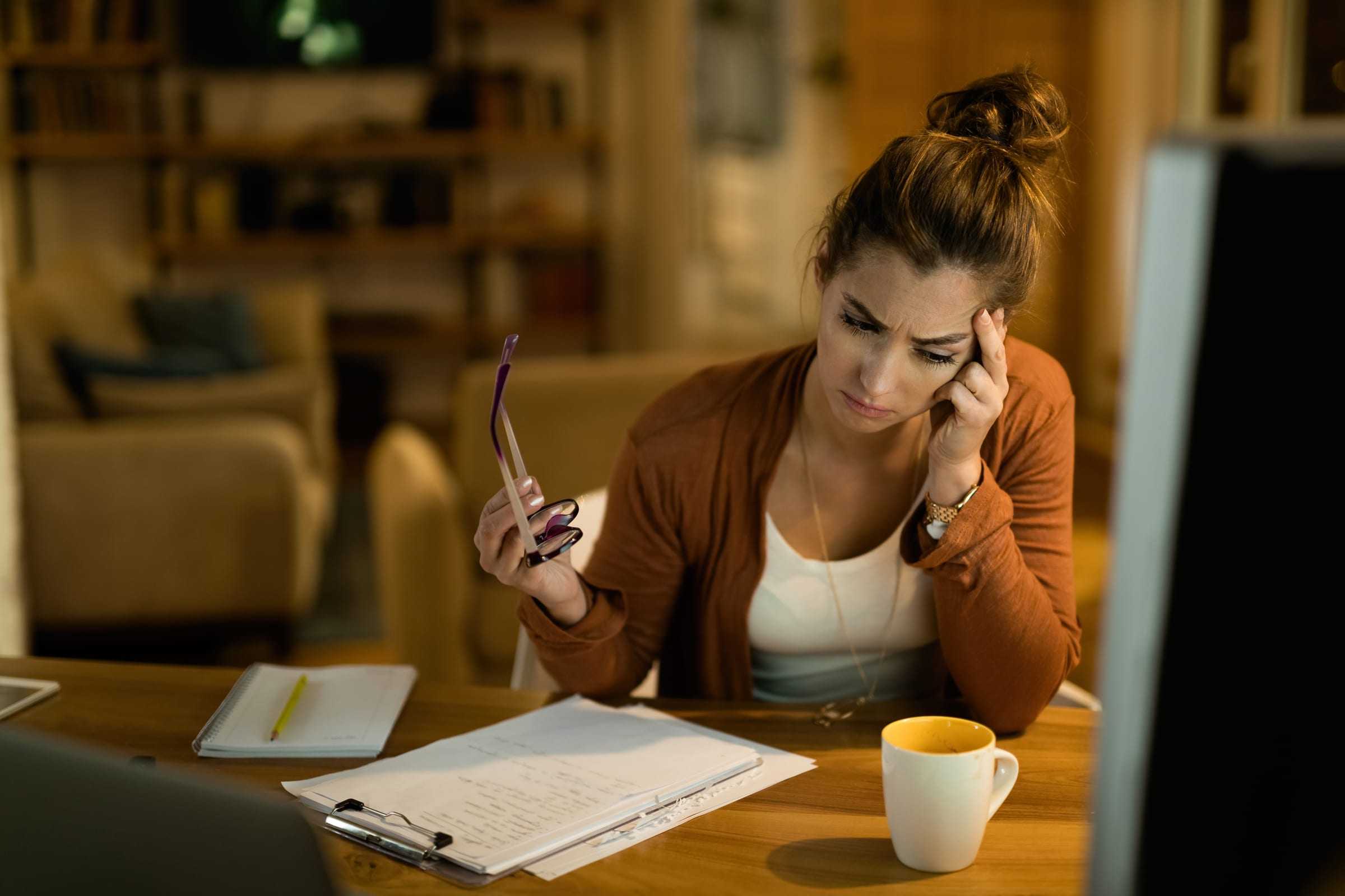 Persona leyendo documentos y tomando notas sobre la mesa de su casa